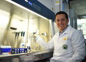 Foto del Dr. Rodrigo Mora, posando sentado en el laboratorio, sonriendo.