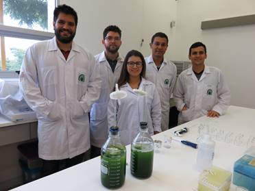 Cinco investigadores posan en el laboratorio, todos de pie sonriendo.