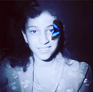 Foto artística de Yarima en su edad adolescente sonríe y una mariposa morpho posa cerca de su ojo izquierdo.