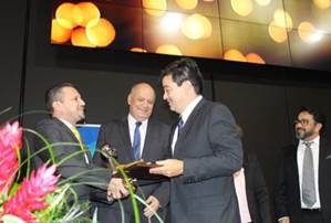 Foto donde el Dr. Hugo Hidalgo recibe el galardón 2018 por parte del Ministro de Ciencia, Tecnología y Telecomunicaciones don Luis Adrián Salazar, ambos sonríen.