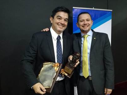 Foto del Dr. Hidalgo con su galardón y a su lado el Ministro de Ciencia con su mano en el hombre del doctor; ambos sonríen.