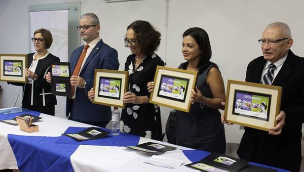 Representantes de Correos de Costa Rica y de la Academia Nacional de Ciencias de pie frente a una mesa, muestran la emisión postal enmarcada.
