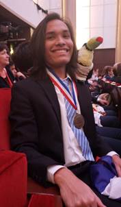 Foto del ganador de la medalla de bronce, Fabrizio Salas Ramírez  sentado con su medalla en el cuello, sonriendo.