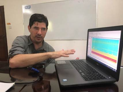 Foto del Dr. Hilje sentado en su escritorio mostrando en su computadora el trabajo que realiza.
