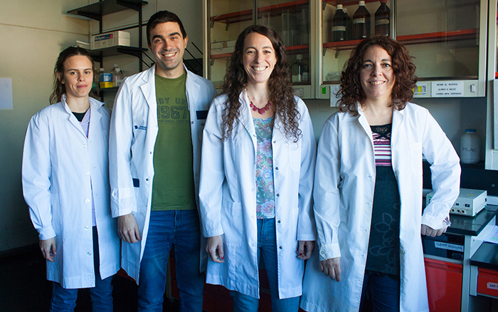 Cuatro investigadores posan en el laboratorio con gabachas blancas, sonríen. 