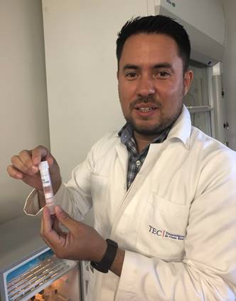 Foto del Dr. Masis en su laboratorio posando de pie con un tubo de ensayo en la mano.