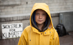 Foto de Greta Thunberg posa de pie con una capa amarilla, foto de medio cuerpo