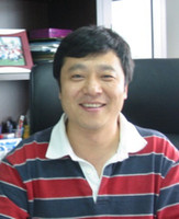 Foto de medio cuerpo de Hongkui Deng, posa sentado sonriendo.