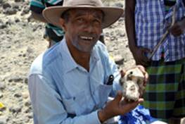 Foto de medio cuerpo de Yohannes Haile-Selassie, posa sentado con unos huesos en la mano haciendo trabajo de campo.