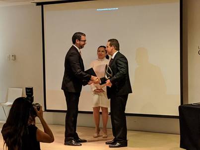 El Dr. Arrieta recibe el galardón y da un apretón de manos al Dr. Fernando García.