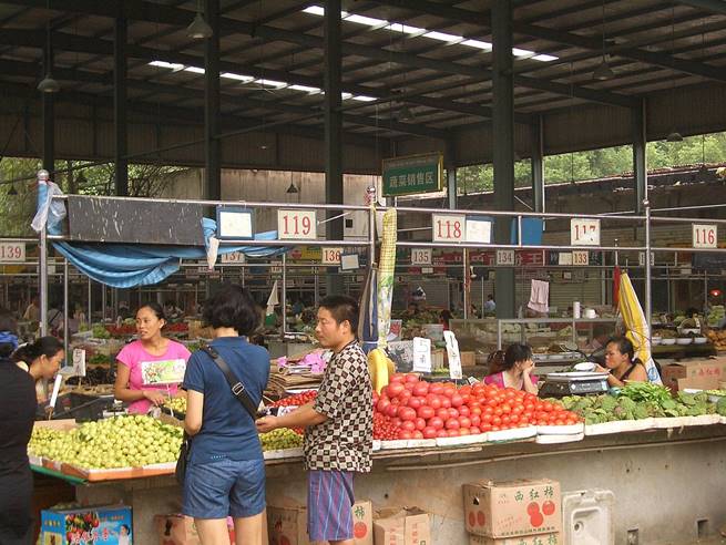 Foto ilustrativa, un mercado de frutas, varias personas de nacionalidad china vendiendo y comprando.