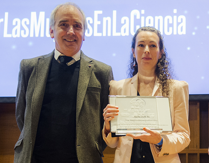 Marina González posa mostrando su certificado de mención especial junto a un representante del Premio.