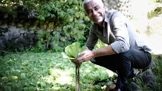 Foto del Dr. Ricardo Radulovich de cuclillas con unas plantas en la mano.