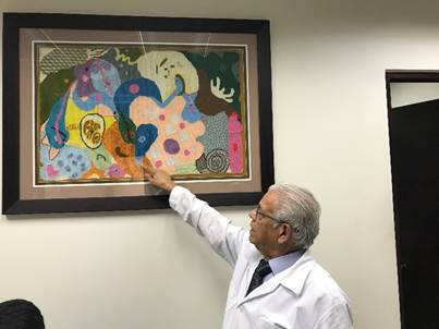 El Dr. Chinchilla muestra un cuadro con un dibujo del tejido de un protozoario, realizado por él.