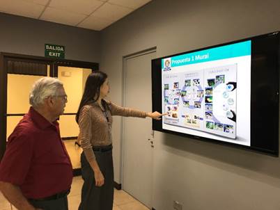 El Dr. Chinchilla de pie junto a otra persona observan uno de los carteles de los resultados de proyectos de investigación.